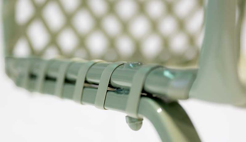 Close-up of a sage green chair frame with strapping secured at the spring base