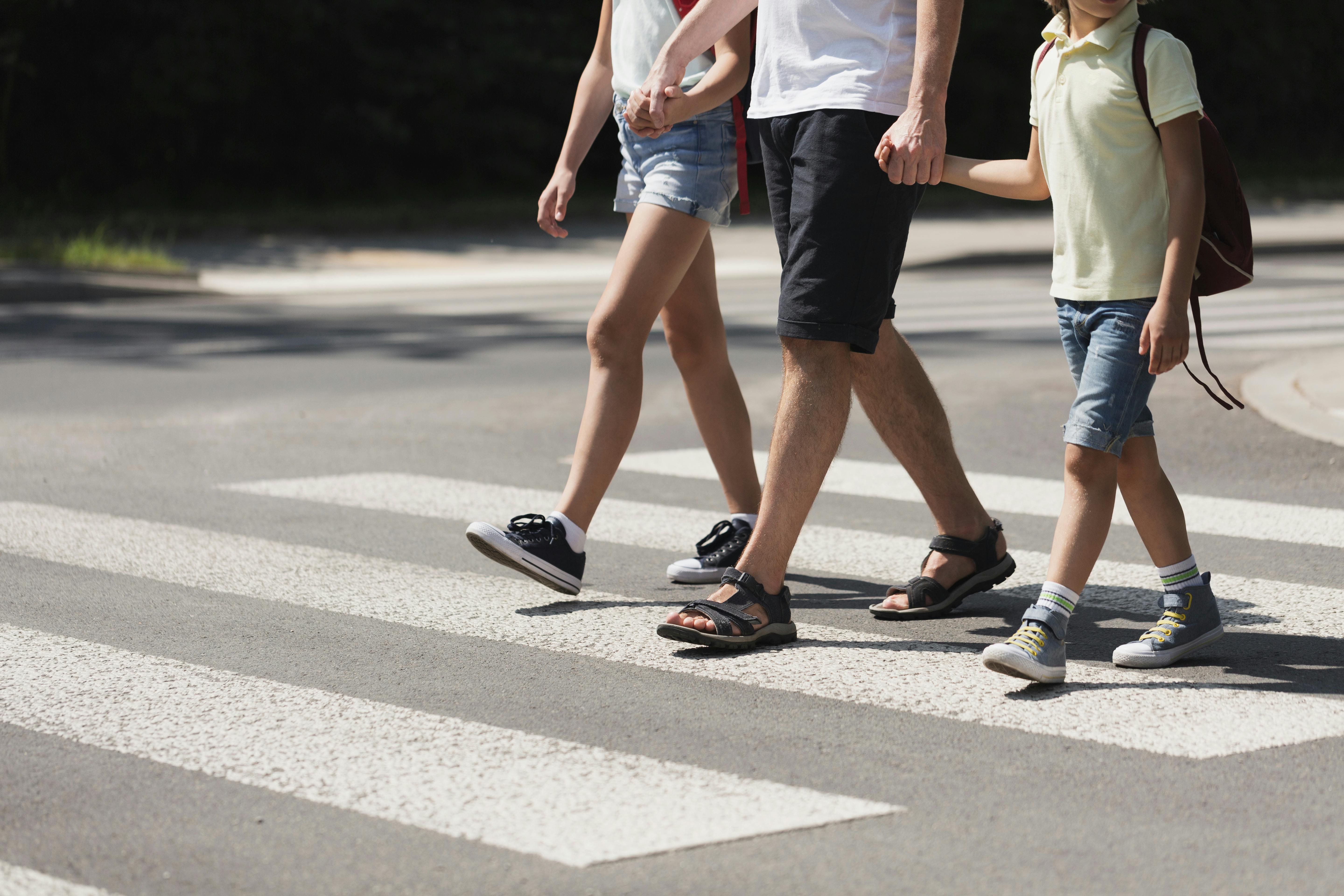 Father holding hands with his kids while on pedestrian crossing