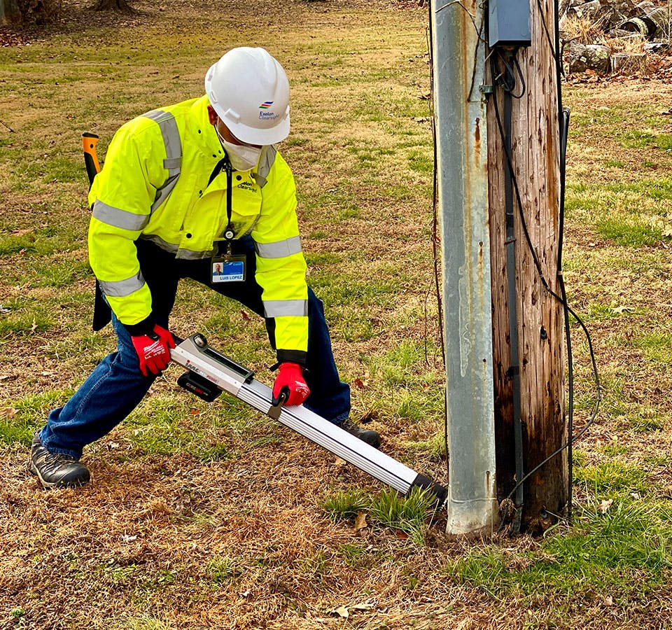 Man performing a wood pole inspection, treatment, and reinforcement (ITR)