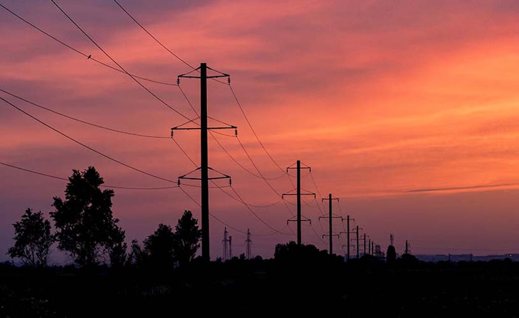 pink orange sunset behind a series of utility poles