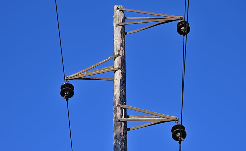 Vintage electric pole and wires. An old overhead power line and single wood utility pole structure.