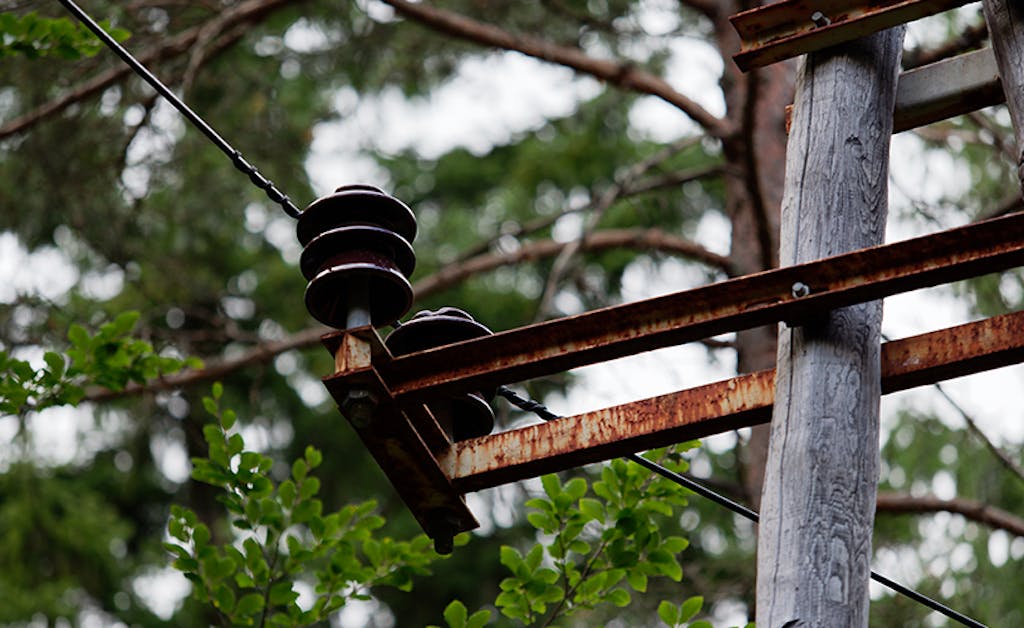 Close up of an electric power line that leads through the forested area in the rural part of the country. 