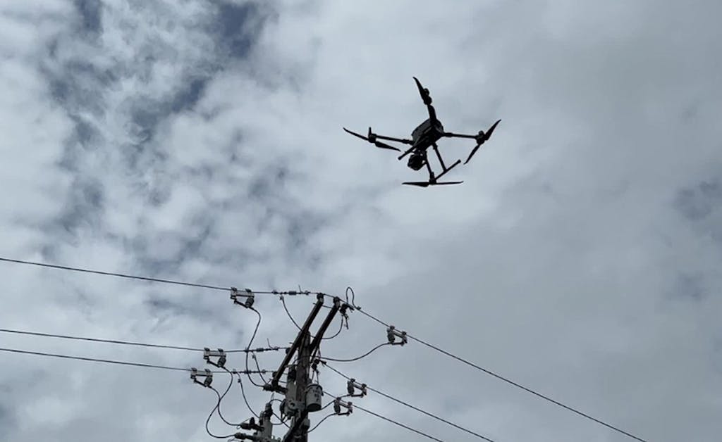 A drone flies near a utility pole during an inspection.