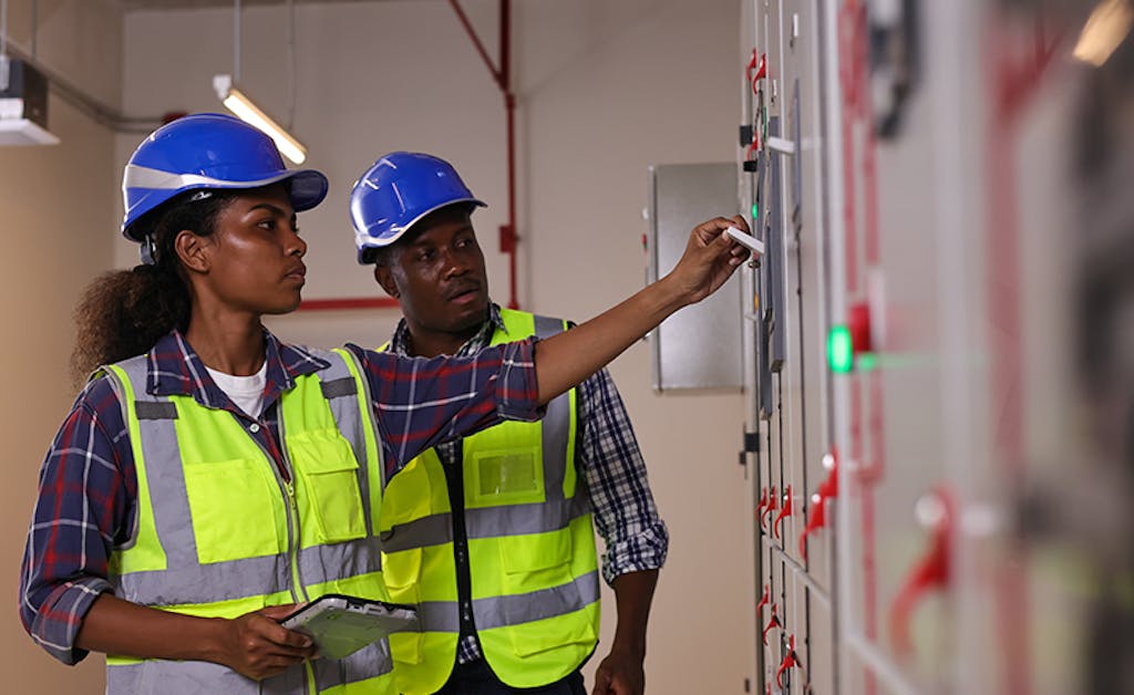 Male and female electrical engineer team working in an industrial electrical control room.