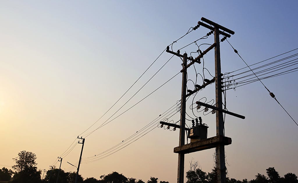 Silhouette of a transformer on a power pole. High voltage transmission lines and three-phase transformers for serving the community.
