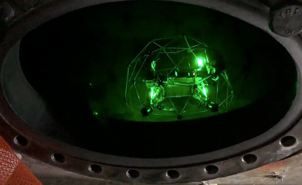 A drone glowing green light inside a confined tube at a generation facility performing an remote visual inspection.