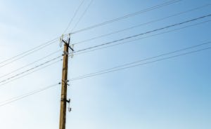 Electric utility pole with line wire under blue sky
