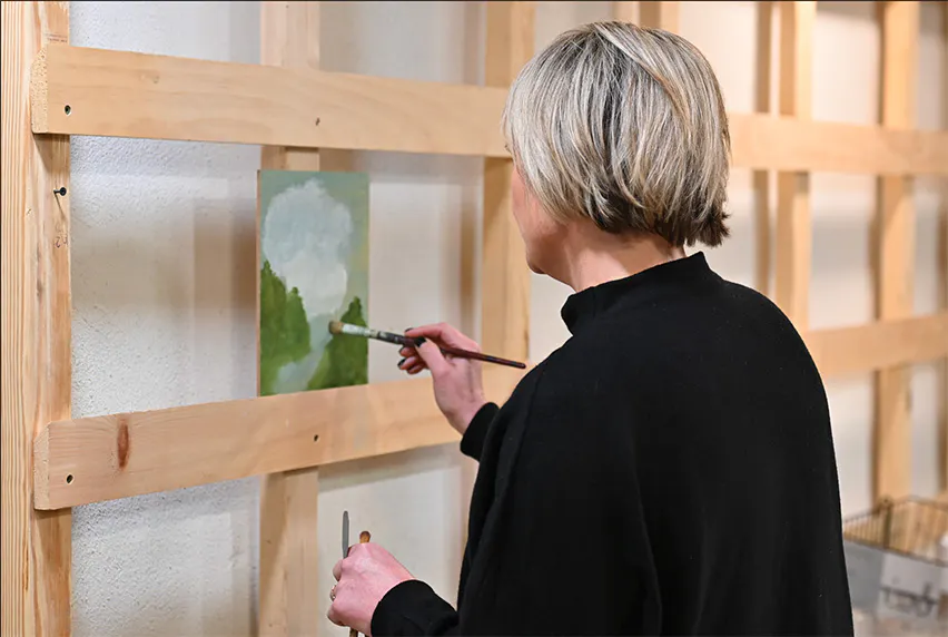 a woman in black sweater painting with brush