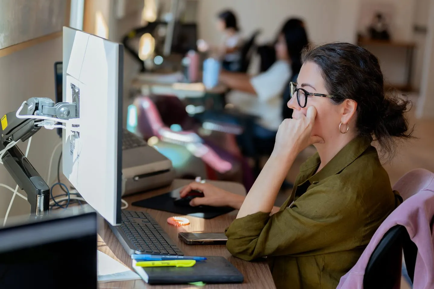 A Media Proper team member focused at her monitor, the team behind her