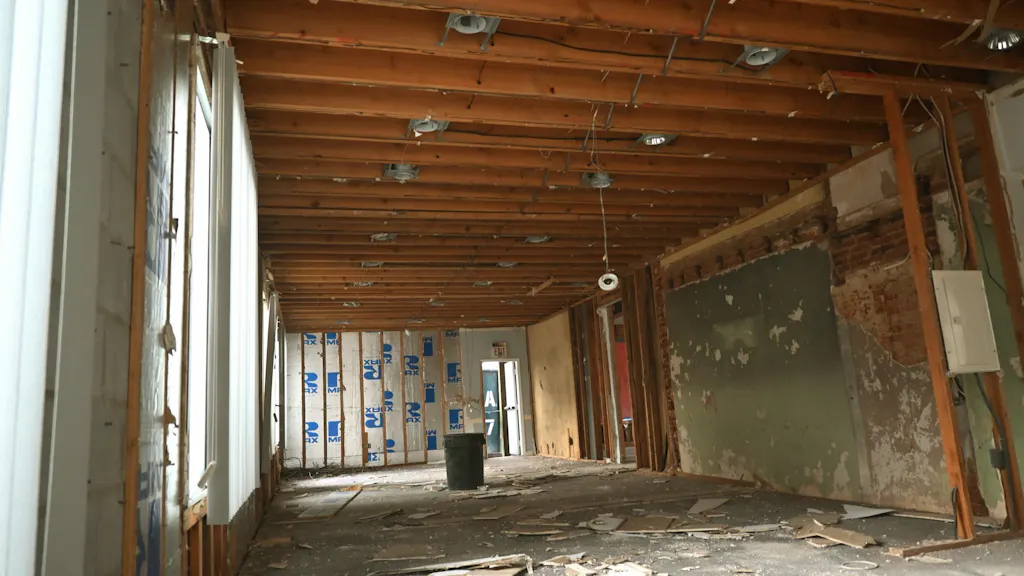 The same office corner mid-demolition: joists open, walls to studs