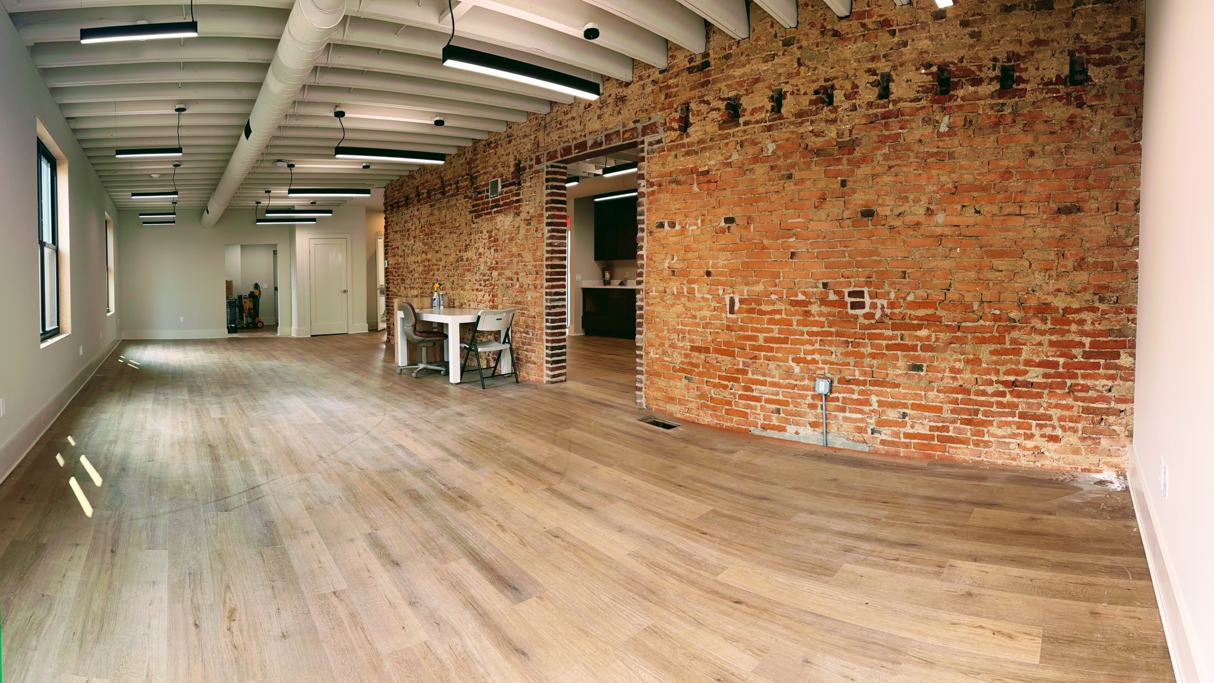 The Media Proper office at 20 W. 3rd Street after the rebuild: exposed brick, new floors, linear lighting