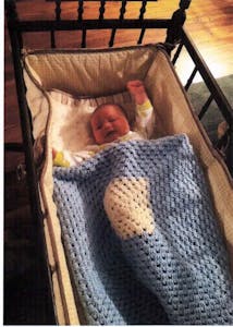 A medical center newborn enjoys the comforts of one of Sr. Ann’s hand-crocheted blankets.