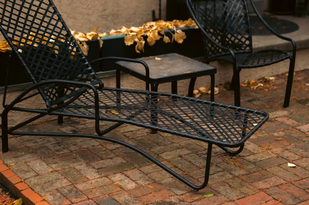 A restored black lattice chaise and side chair on a patio