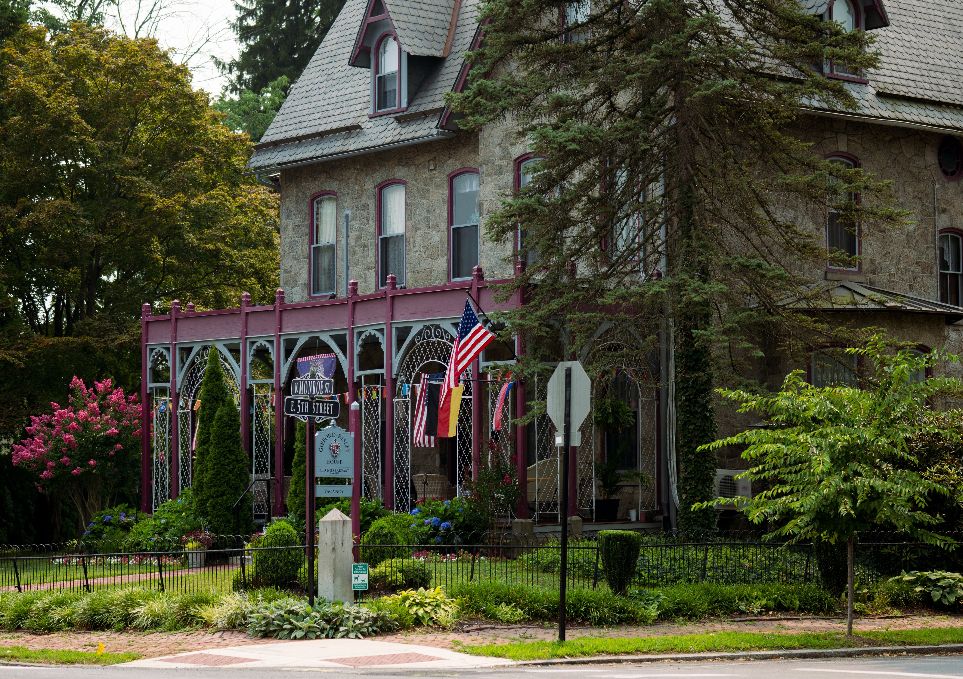 A Victorian stone bed and breakfast in Media with a pink ironwork porch and flags